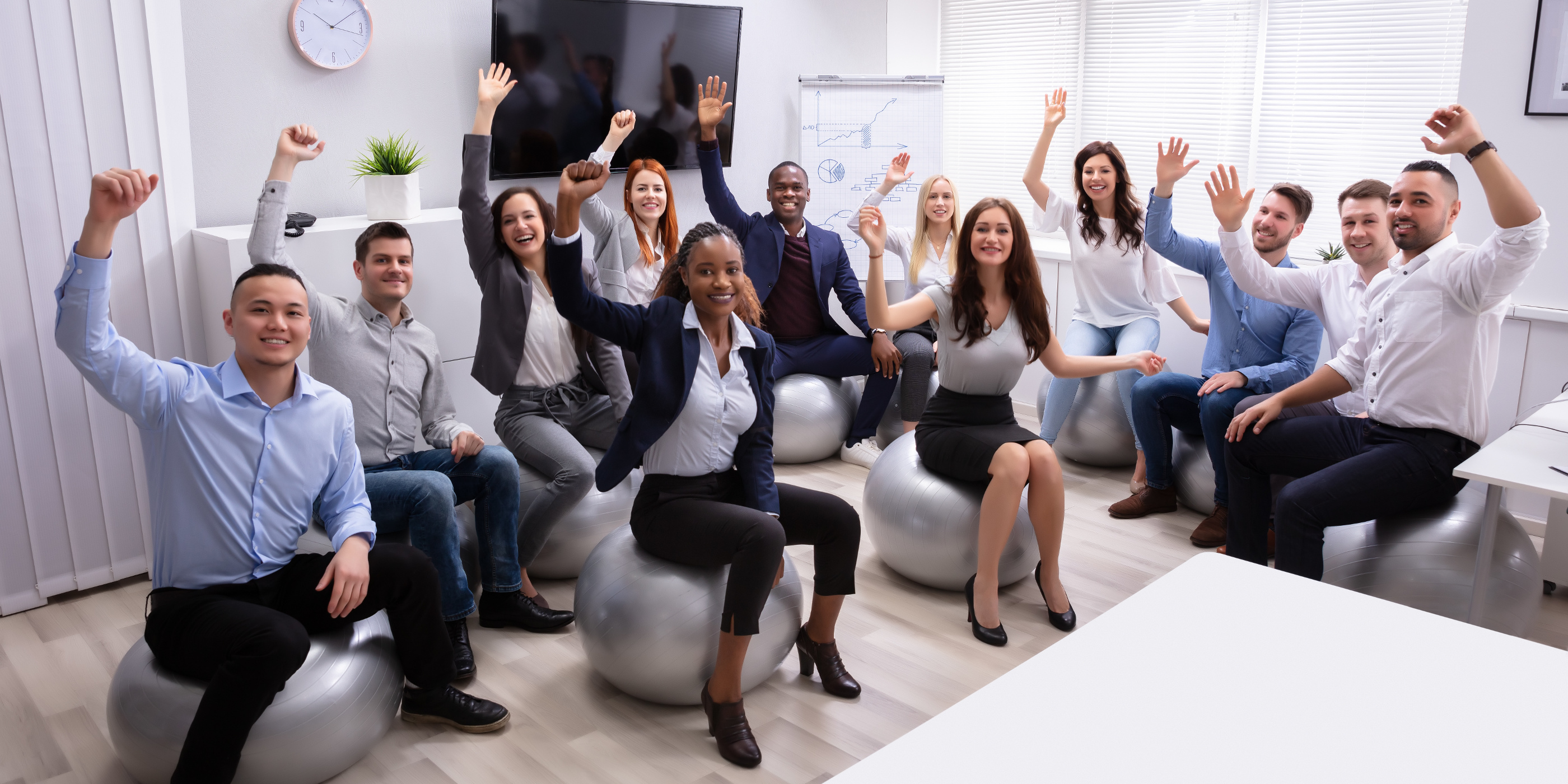 Group of happy employees sitting on exercise balls